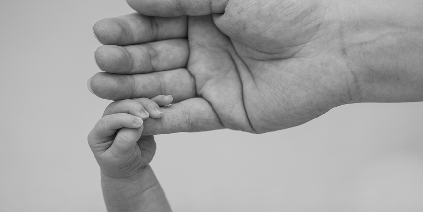 En bebishand som håller i fingret på en vuxenhand.