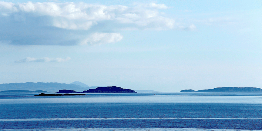 Foto på blått hav och blå himmel, med en liten landremsa i fjärran