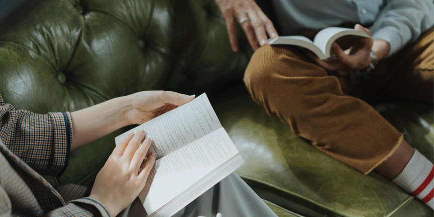 Två personer sitter i en soffa och läser böcker.