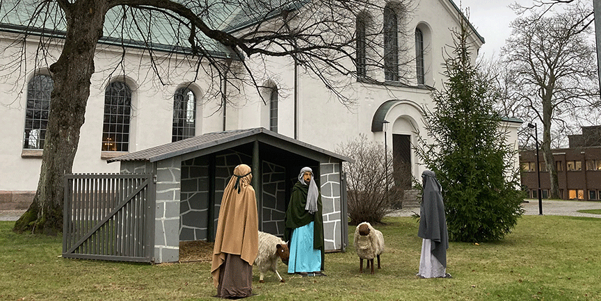 Bilden visar Värnamo kyrka i bakgrunden och framför ser man krubban med Josef och Maria och herdarna.