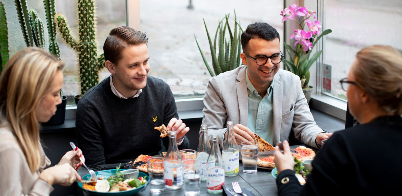 Fyre personer sitter och äter lunch på D8. De skrattar och samtalar med varandra.