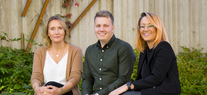 Tre studenter sitter på en bänk på baksidan av Gummifabriken.