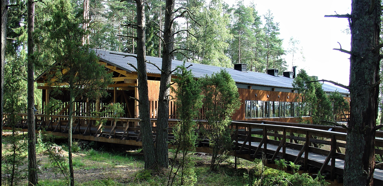 Naturum på Store Mosse nationalpark. En avlång träbyggnad med träd runt den.