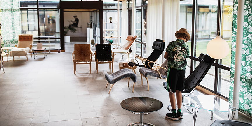 En pojke som tittar på stolar i Bruno Mathsson Center