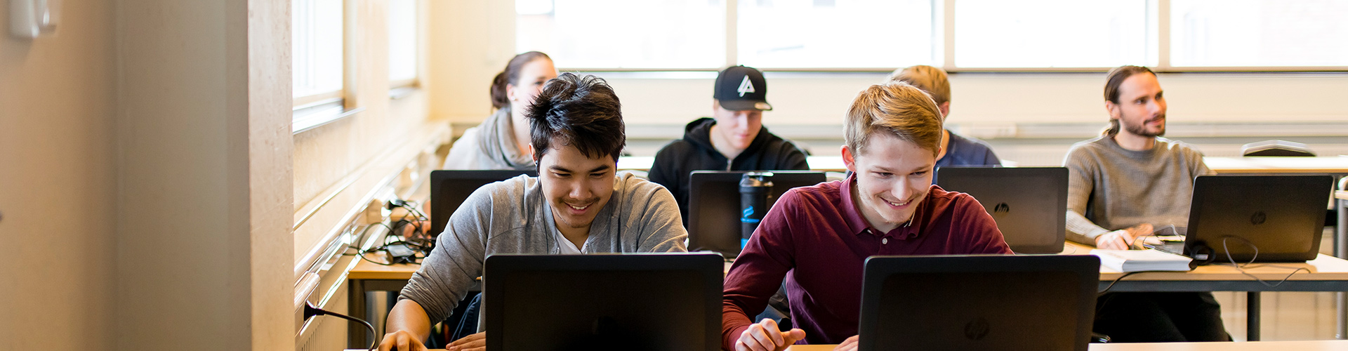Glada studenter i ett klassrum som studerar 3D-teknik.