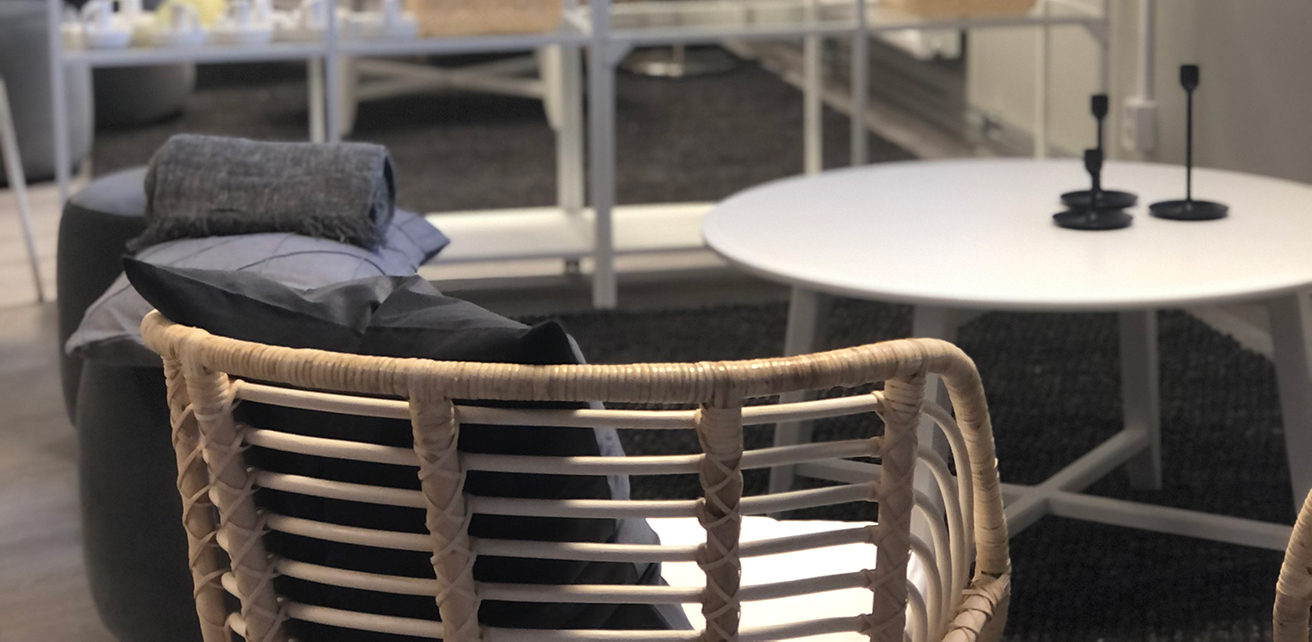 Inredningen inne på Ditt Cafe Livingroom. I förgrunden står en rottingfåtölj, ett bord med tre ljusstakar, och i bakgrunden går det att skymta fler stolar och bord.