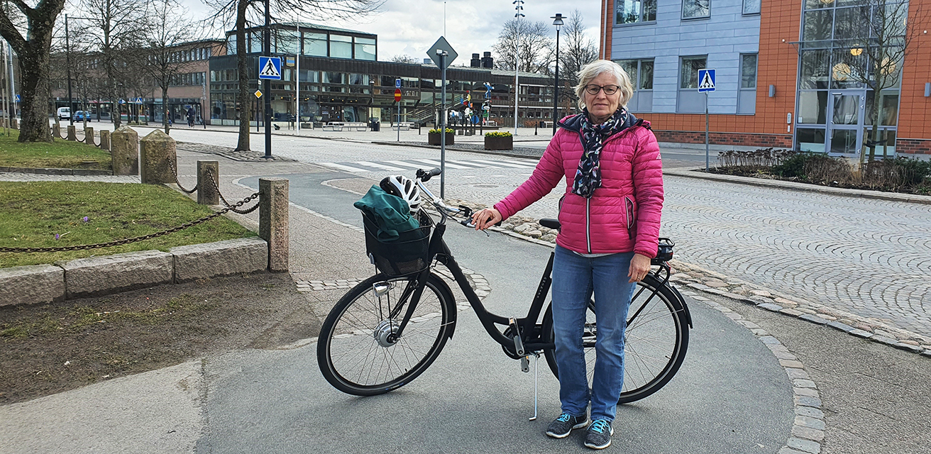 Vinnaren i ordjakten, Görel Magnusson, står vid sin nyvunna elcykel framför Stadshuset, Värnamo.