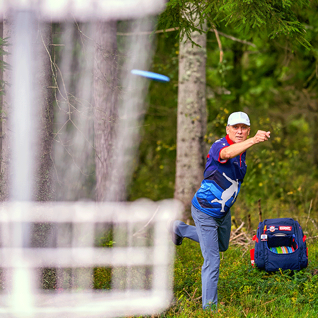 En manlig discgolfspelare står vid en korg.