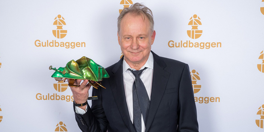 Skådespelaren Stellan Skarsgård håller upp en guldbagge-staty