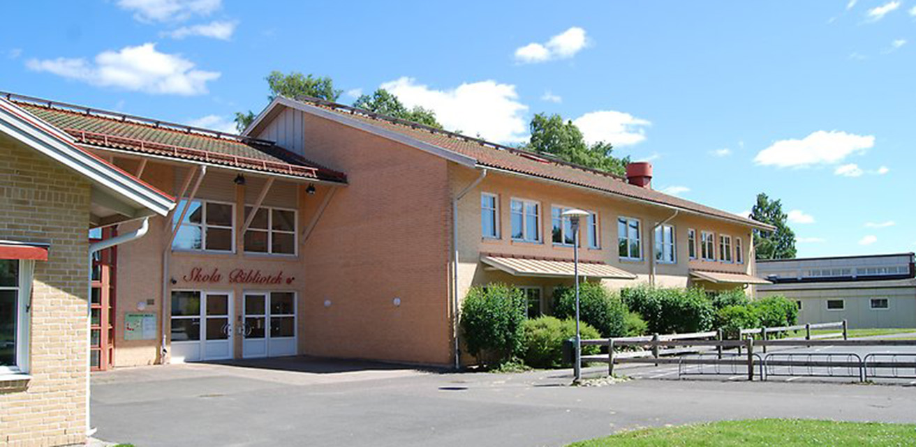 Bygdegården i Bredaryd. En rosa byggnad med skyltar där det står "Skola Bibliotek" över entrédörren.