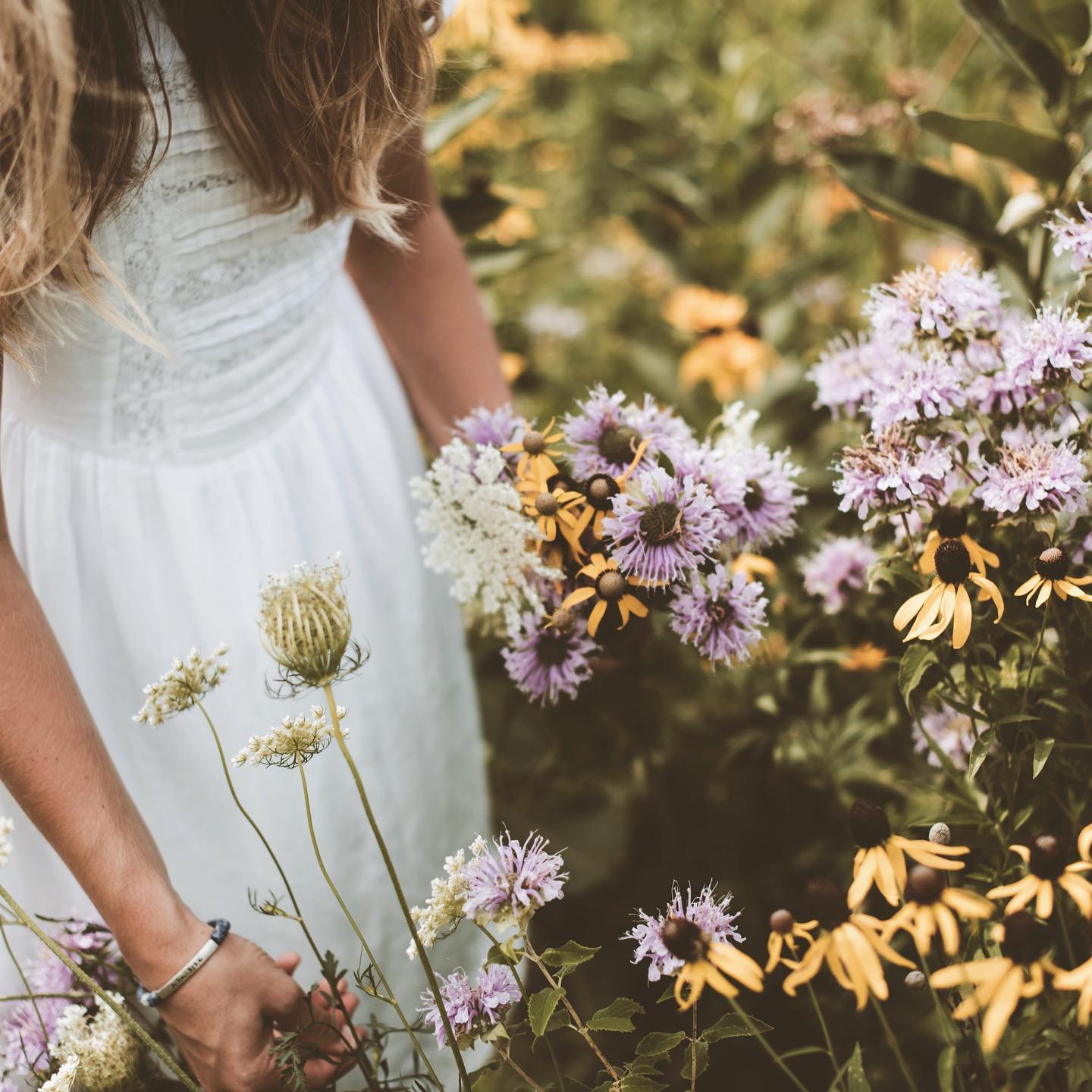 Flicka som plockar blommor på en blomsteräng.