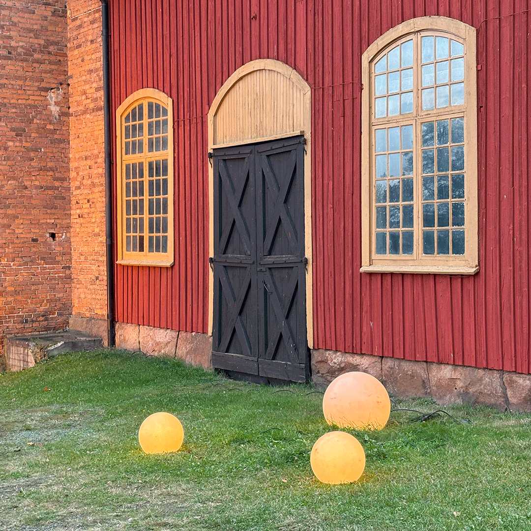 Bilden visar fasaden på Åminne Bruk. Framför ligger tre lysande klot som ger en känsla av jul.
