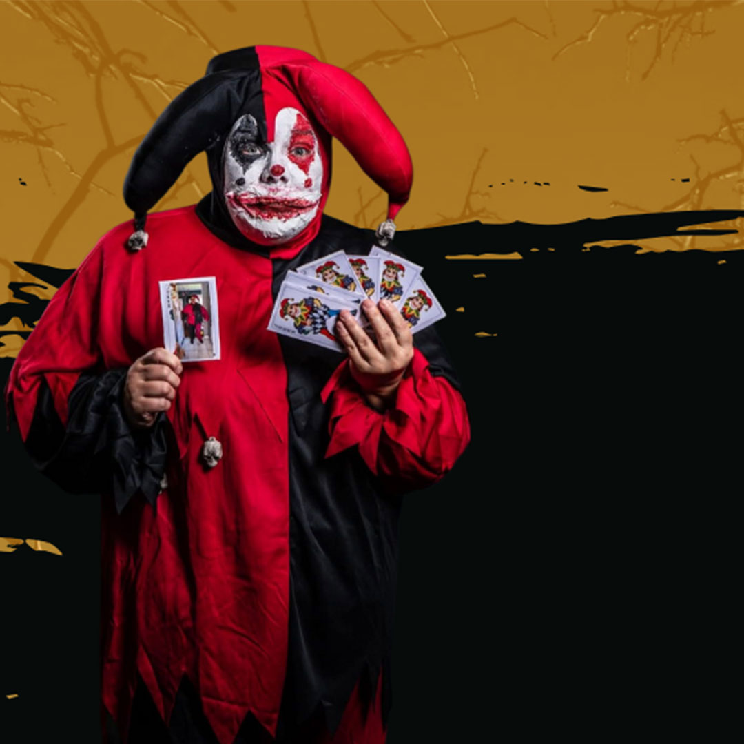 Bilden visar en clown som håller en kortlek. Clownen ser lite läskig ut med sitt målade ansikte.