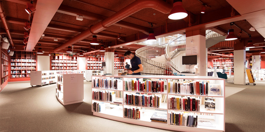 Stadsbibliotekets interiör med rött tak och vita svängda hyllor.