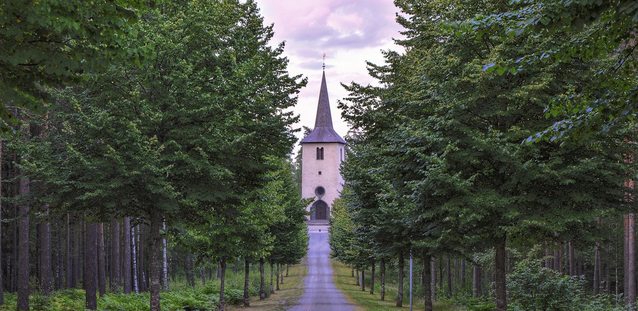 En väg som leder till Ohs kyrka. Det är skog vid sidan av vägen.